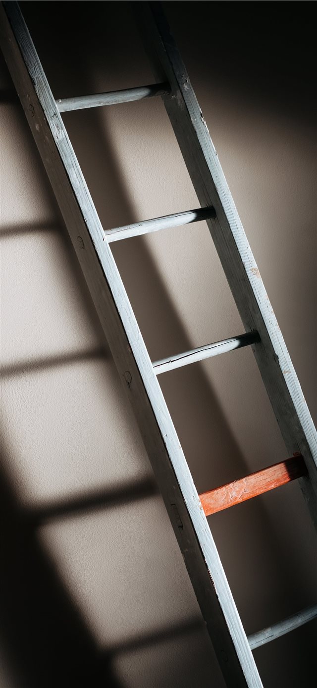 An old wooden ladder casting soft shadows on wall iPhone X wallpaper 