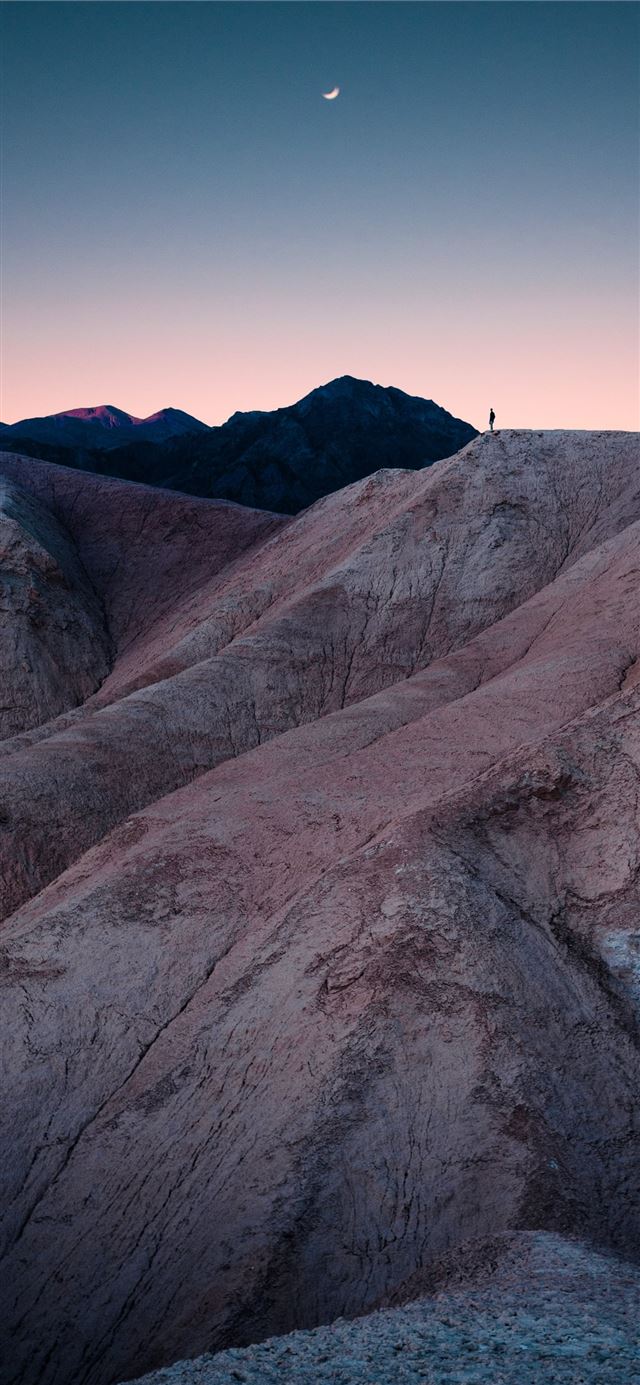 man standing on mountain during daytime iPhone X wallpaper 