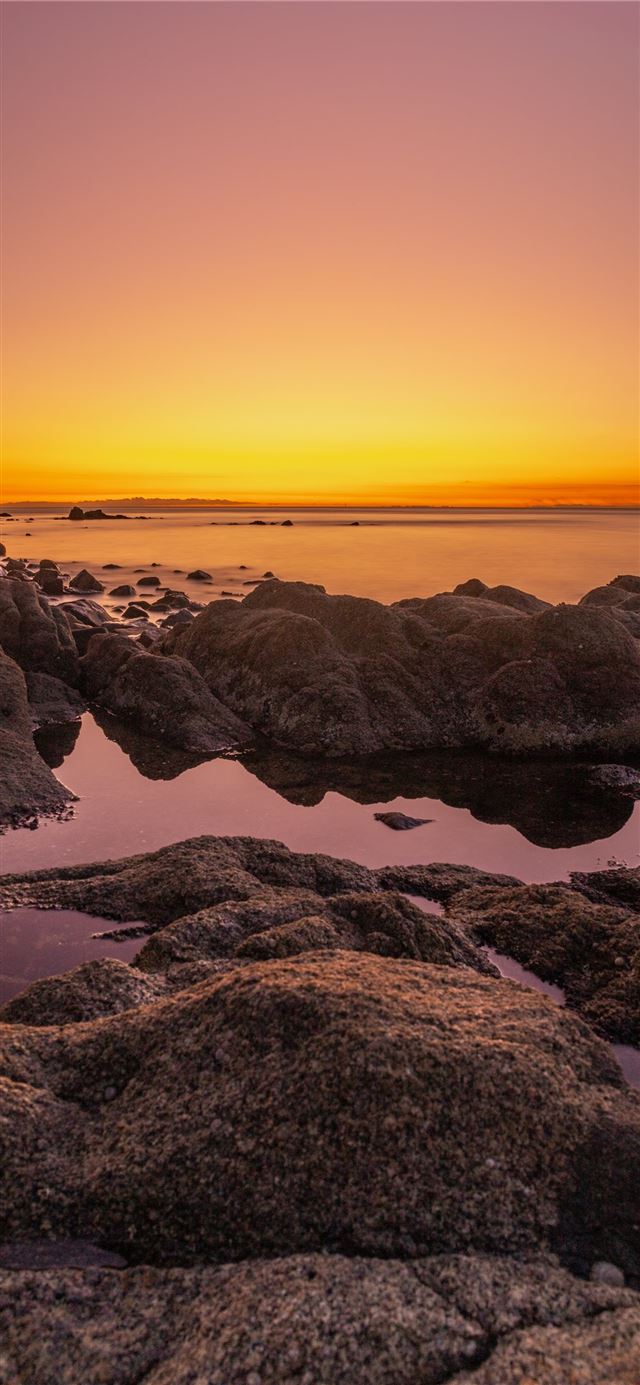 rocky shore during sunset with orange sky iPhone X wallpaper 