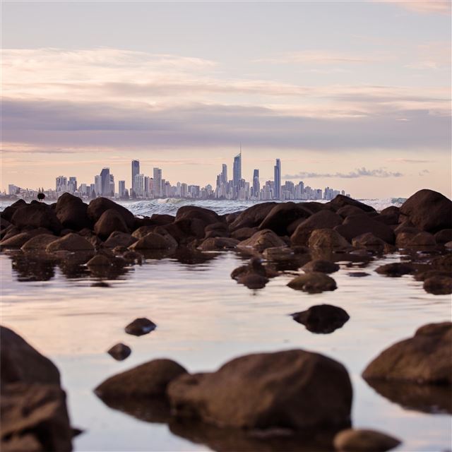 2048x2048 seashore rocks near city view of buildings 5k - city iPad Air Wallpaper