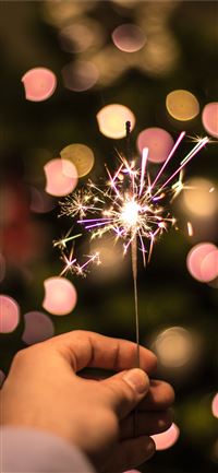 bokeh photography of person holding fireworks wallpaper