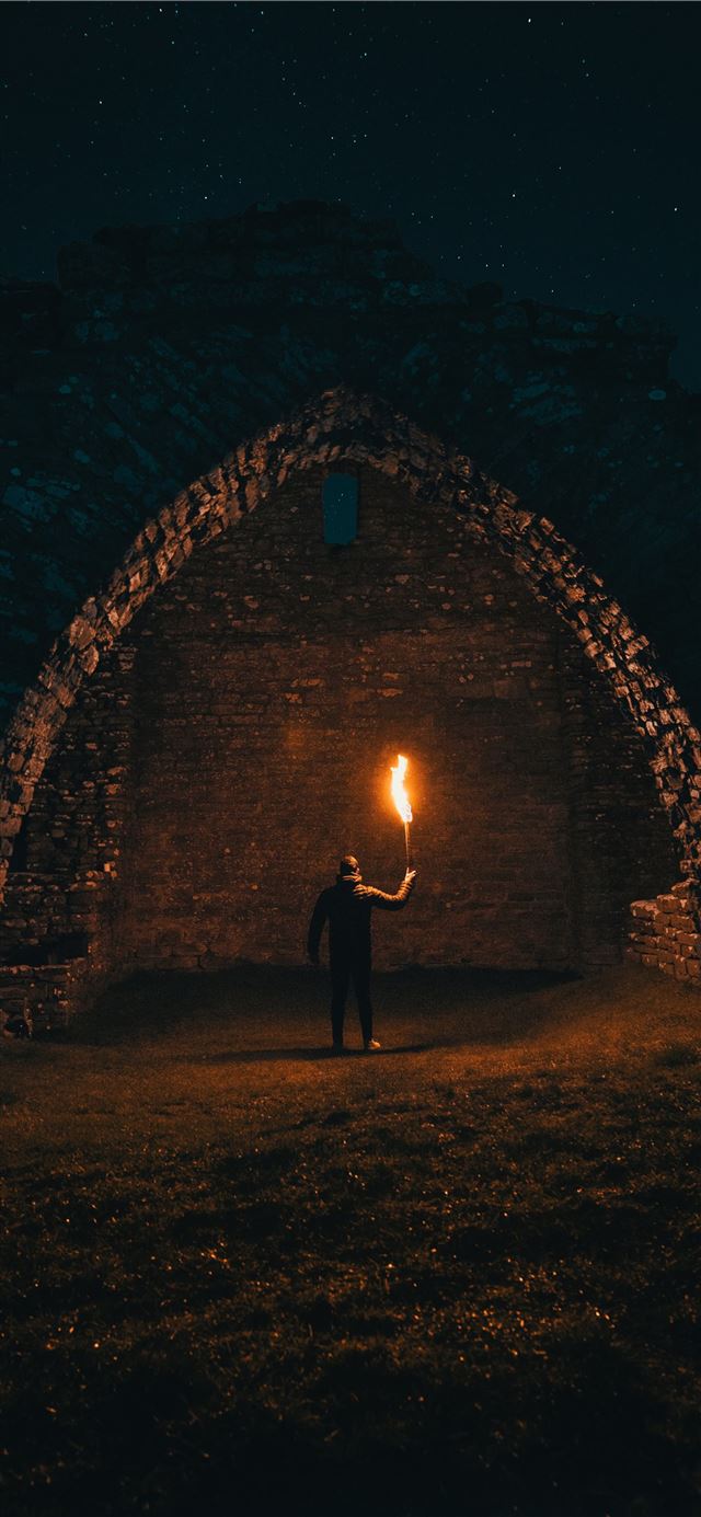 1125x2436 person holding torch in building interior - dark (black) iPhone 11 Wallpaper