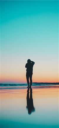silhouette of person in seashore during daytime iPhone 11 wallpaper