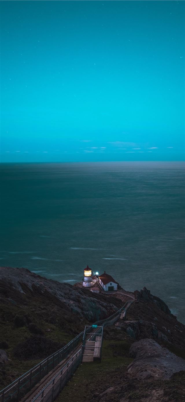 1125x2436 brown and white house on cliff in front of sea - ocean iPhone 11 Wallpaper
