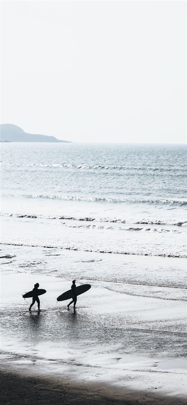 1125x2436 two people carrying surfboards at beach during day... - water iPhone 11 Wallpaper