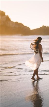 selective focus photo of woman standing on sea sho... iPhone 11 wallpaper