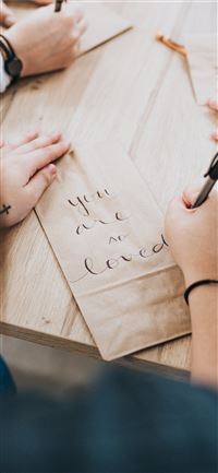 person writing on brown paper wallpaper