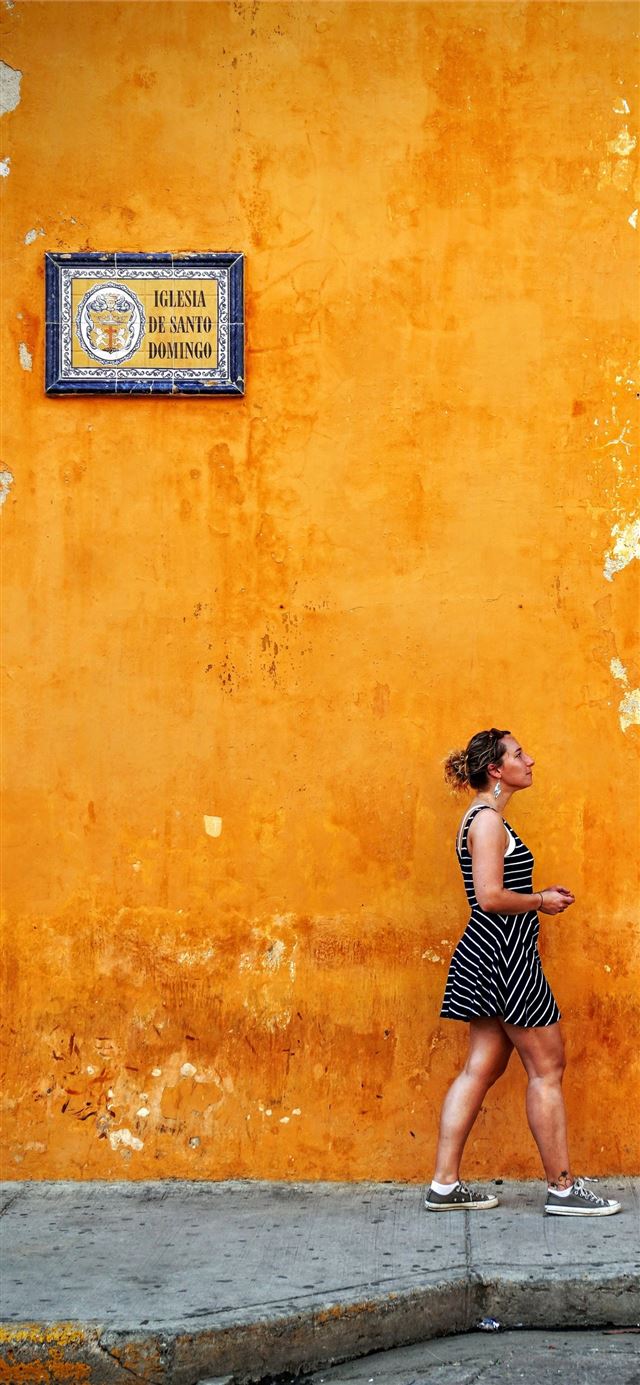 1125x2436 woman walking on sidewalk - orange iPhone 11 Wallpaper