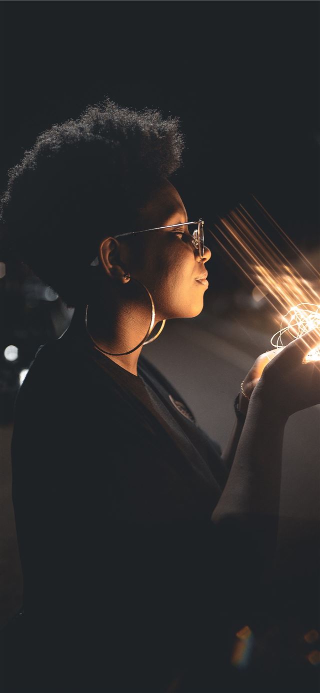 1125x2436 woman standing and holding string lights - black iPhone 11 Wallpaper