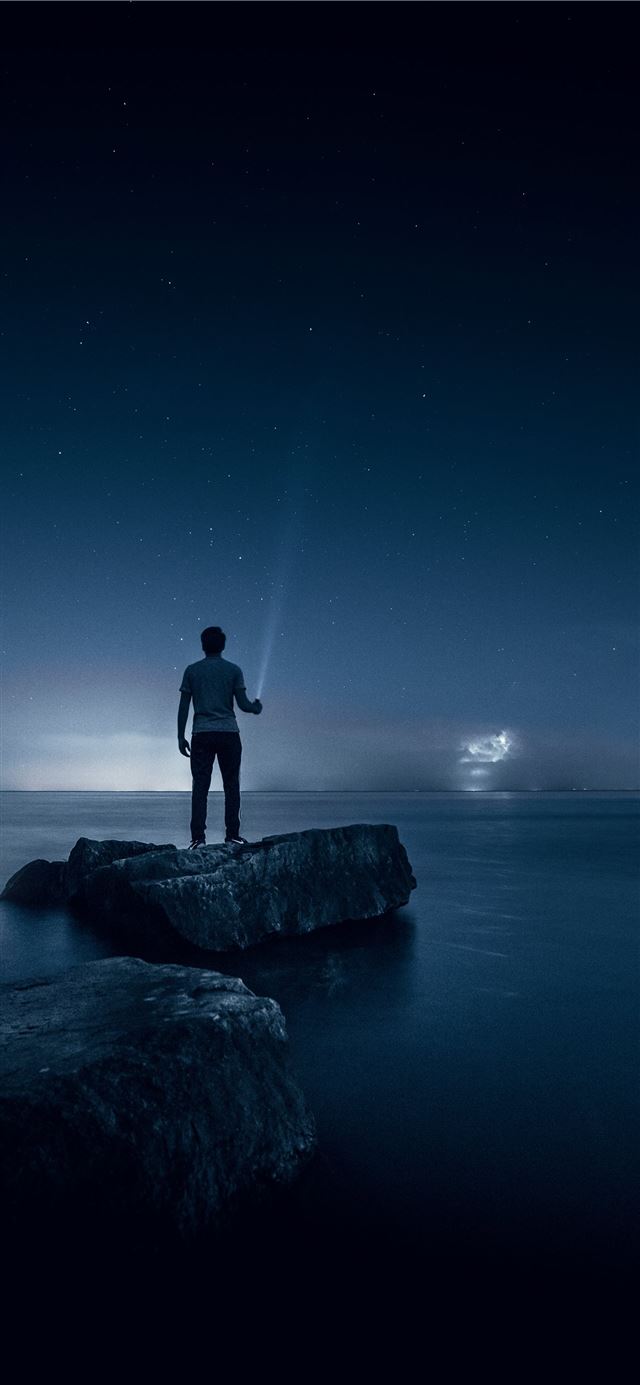 1125x2436 man holding flashlight standing on rock - star iPhone 11 Wallpaper