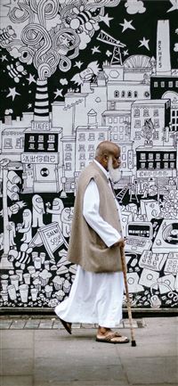 man wearing white sherwani robe beside graffiti wallpaper