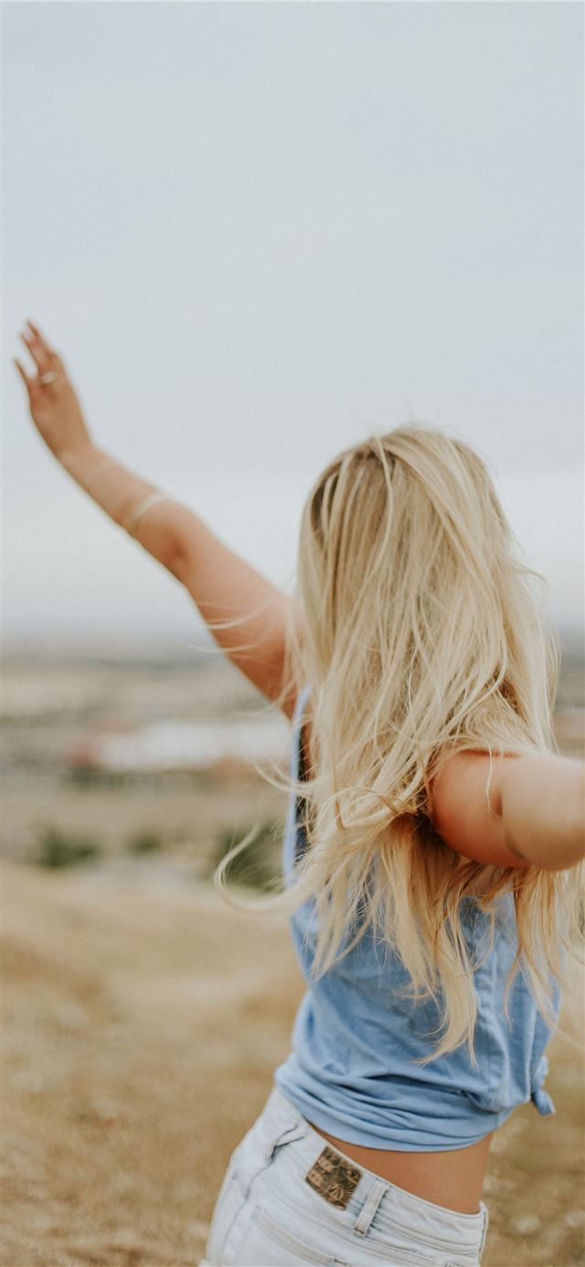 1125x2436 woman wearing blue top while standing on plain fie... - girls iPhone 11 Wallpaper