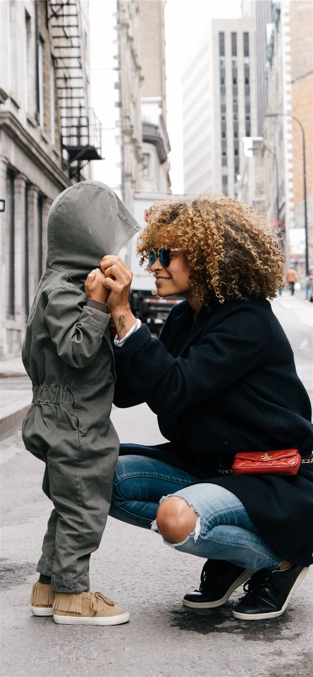 1125x2436 woman holding kid at the street - montreal iPhone 11 Wallpaper