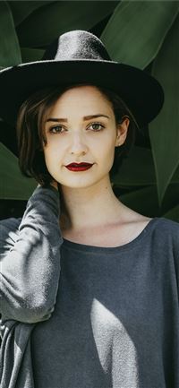 woman standing near trees wearing black hat wallpaper