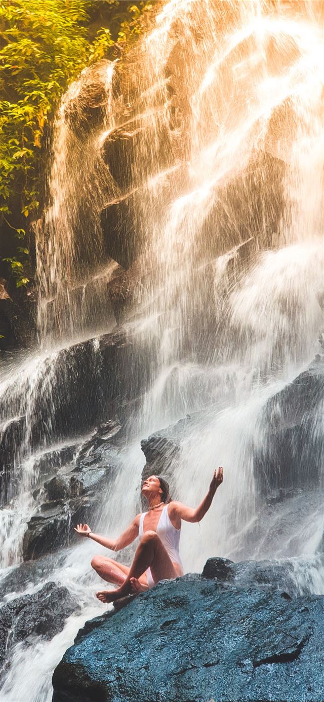 1125x2436 woman in white monokini sitting on rock - bali iPhone 11 Wallpaper