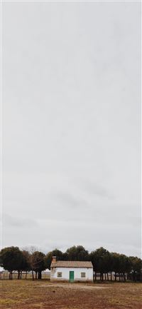 white house beside trees in front brown field wallpaper