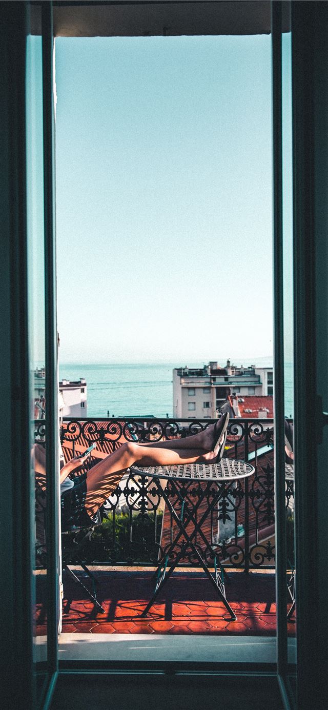 1125x2436 person sitting on balcony - france iPhone 11 Wallpaper