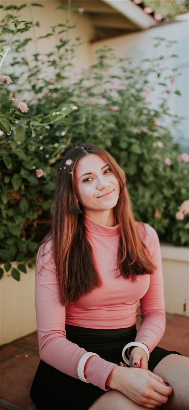 1125x2436 woman sitting near pink flowers at daytime - palm springs iPhone 11 Wallpaper