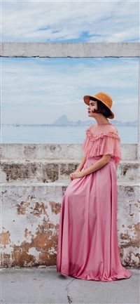 woman wearing pink dress standing next to white wa... iPhone 11 wallpaper