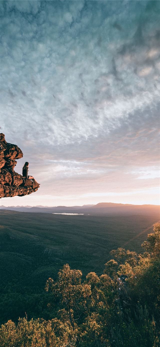 1125x2436 man sitting on mountain rock - sunset iPhone 11 Wallpaper