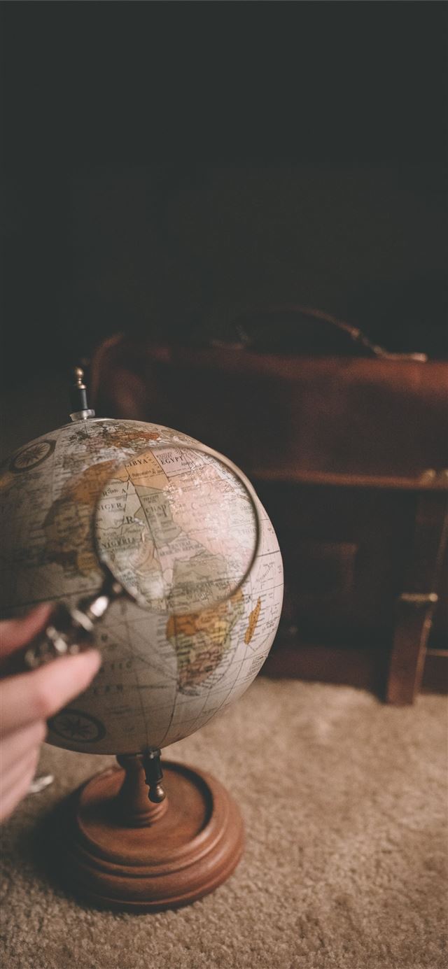 1125x2436 person holding magnifying glass near desk globe - earth iPhone 11 Wallpaper