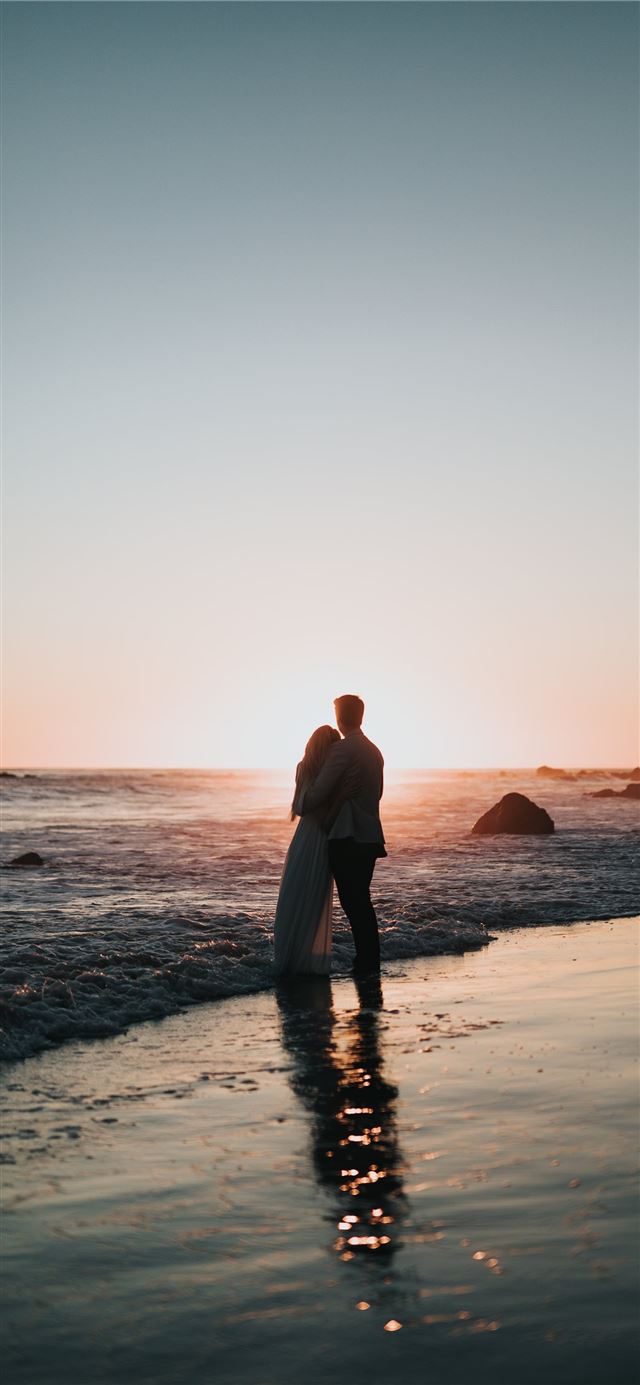 1125x2436 silhouette photo of couple standing on beach watch... - love iPhone 11 Wallpaper