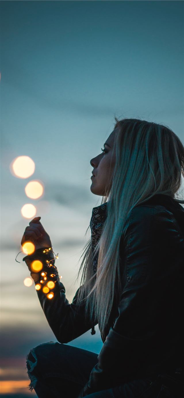 1125x2436 woman sitting holding string lights -  iPhone 11 Wallpaper