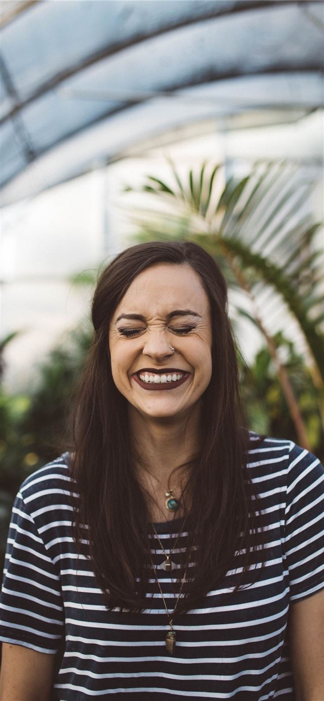 1125x2436 woman smiling while standing in garden -  iPhone 11 Wallpaper