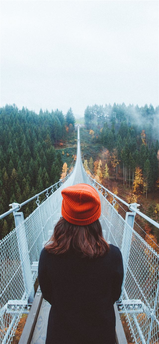 1284x2778 woman wearing knit cap walking on white bridge bet... -  iPhone 11 Wallpaper