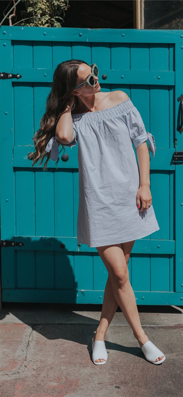 1284x2778 woman touching her hair standing near teal gate -  iPhone 11 Wallpaper