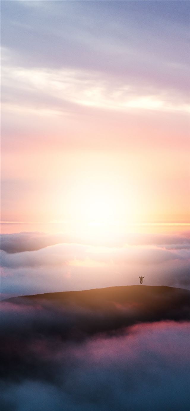 1125x2436 man jumping on hill during golden hour - sunset iPhone 11 Wallpaper
