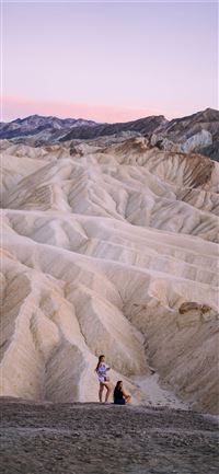 two people standing near sand dunes wallpaper
