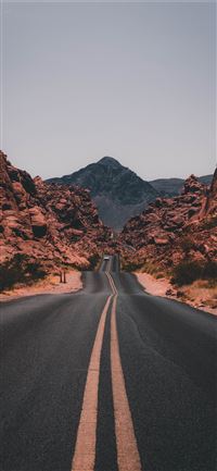 black concrete road surrounded by brown rocks iPhone 11 wallpaper