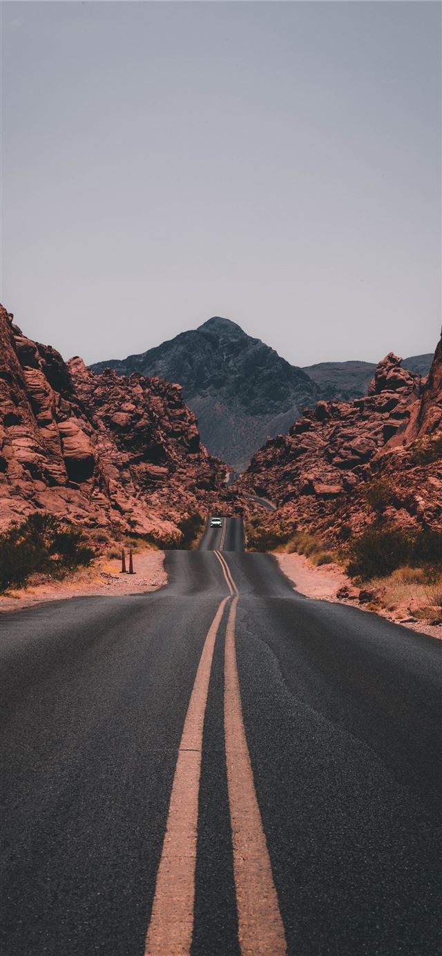 1125x2436 black concrete road surrounded by brown rocks - united states iPhone 11 Wallpaper