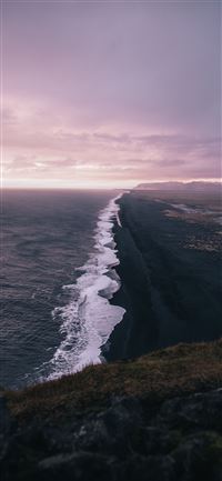waves crashing on shore under cloudy sky during da... iPhone 11 wallpaper