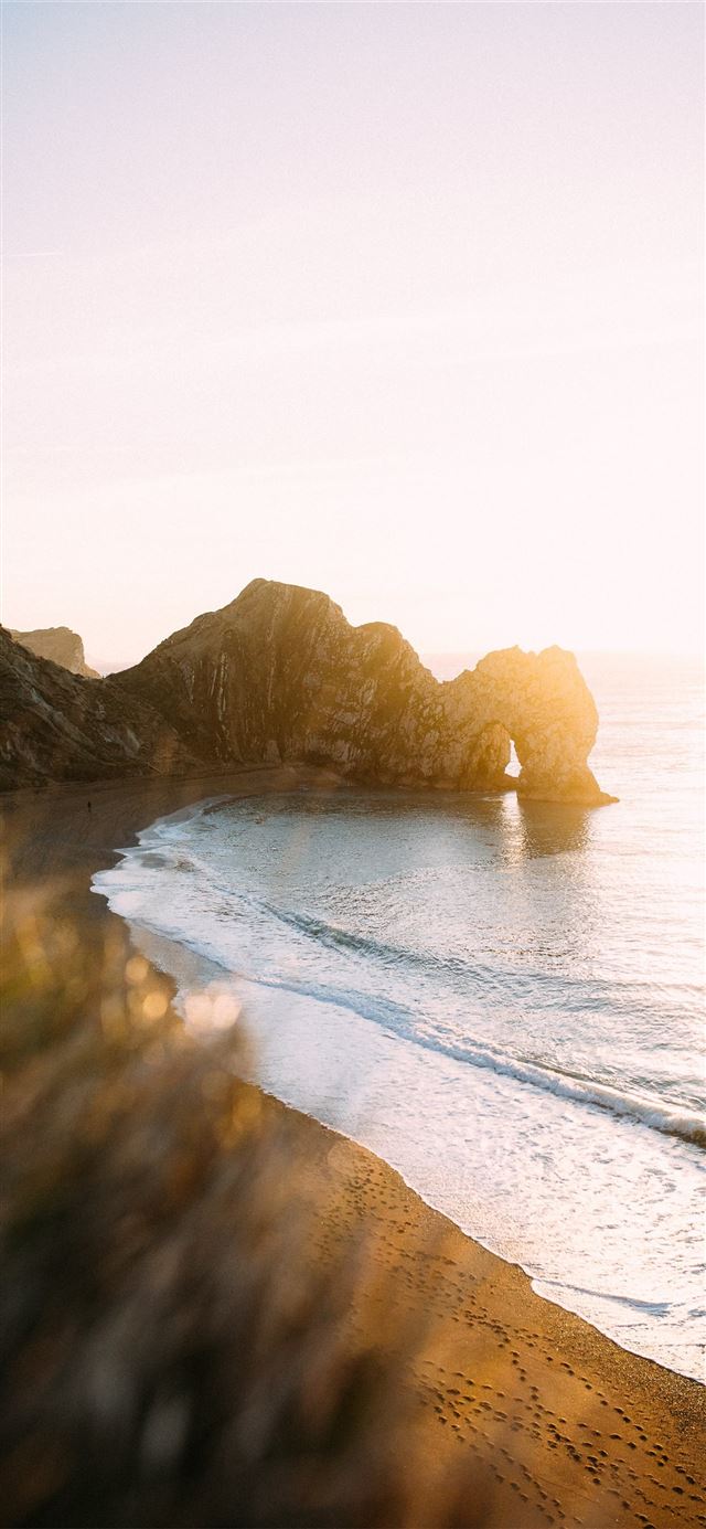 1125x2436 rock monolith beside calm body of water - ocean iPhone 11 Wallpaper