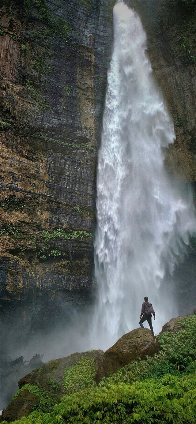 1125x2436 person standing on brown rock formation looking at... - indonesia iPhone 11 Wallpaper