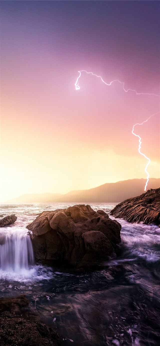 1125x2436 rock formation near sea under thunder light - sunset iPhone 11 Wallpaper