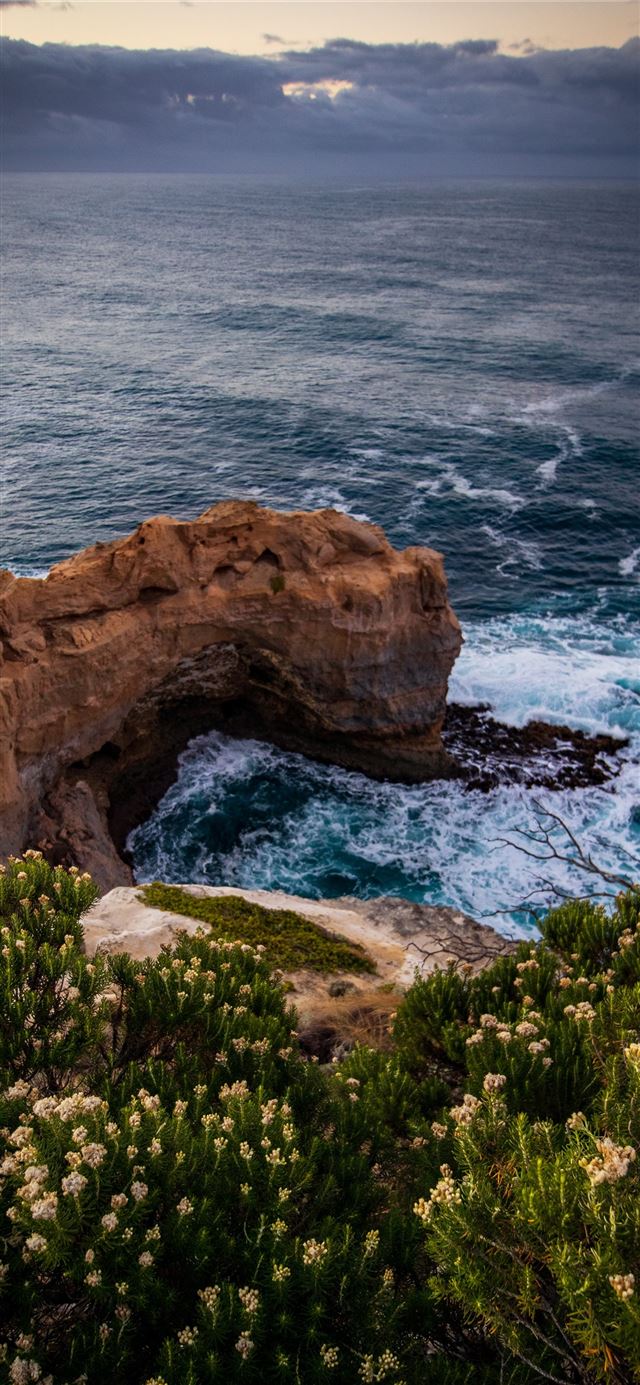 1125x2436 ocean wave crashing on rocky island during day - cave iPhone 11 Wallpaper
