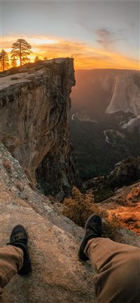 person pair of shoes and sitting on edge of mounta... wallpaper