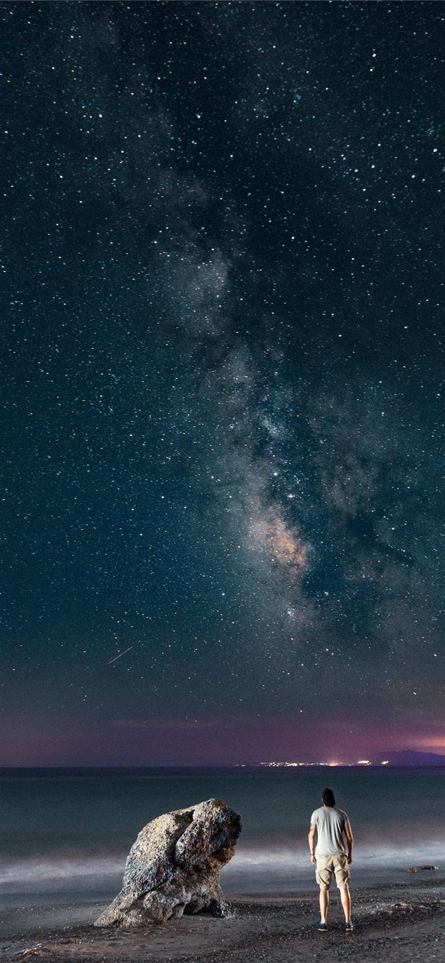 1125x2436 man standing near rock viewing calm sea - grey iPhone 11 Wallpaper