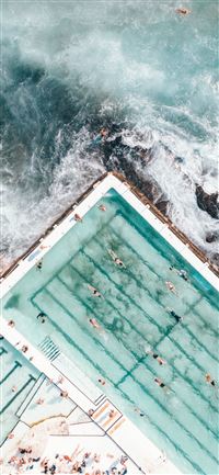 pool with people swimming nearby seashore iPhone 11 wallpaper