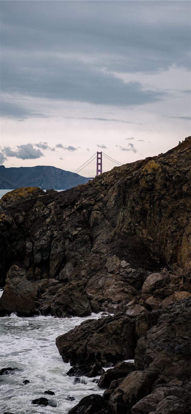 1125x2436 brown rock formation near bridge under white cloud... - water iPhone 11 Wallpaper