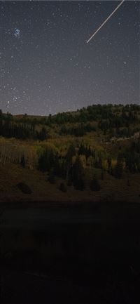 shooting star over green mountain during nighttime iPhone 11 wallpaper