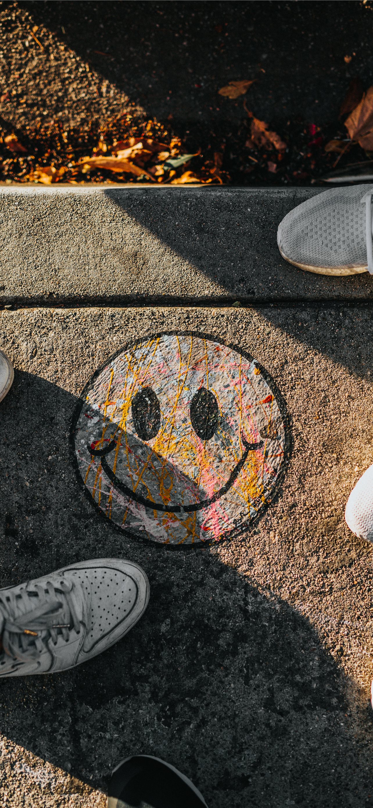 smiley paint on gray ground in front of people iPhone wallpaper 
