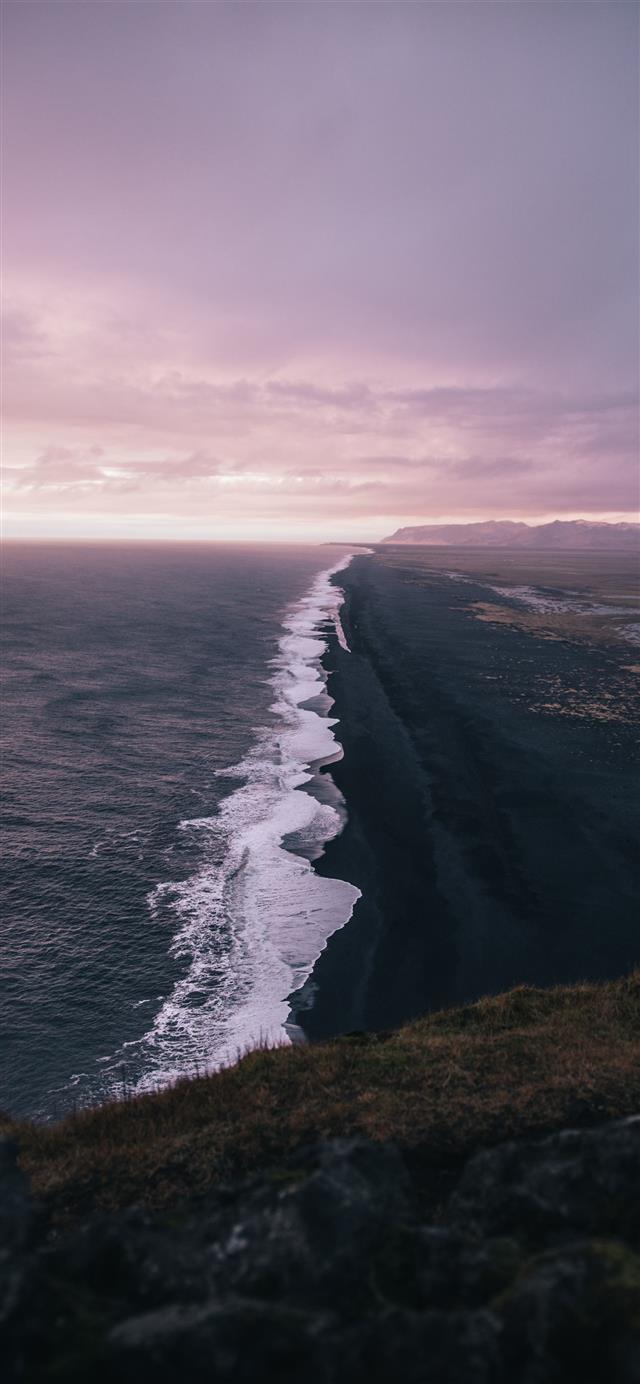 waves crashing on shore under cloudy sky during da... iPhone 12 wallpaper 