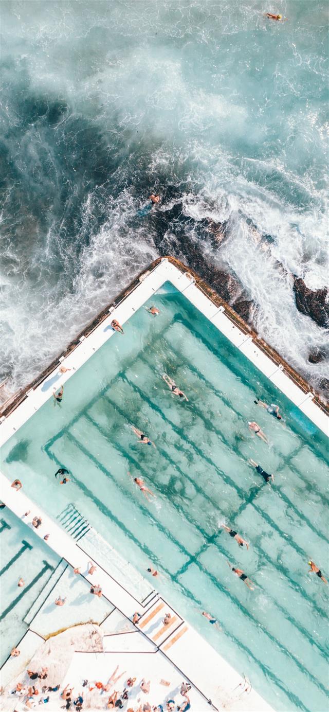 pool with people swimming nearby seashore iPhone 12 wallpaper 