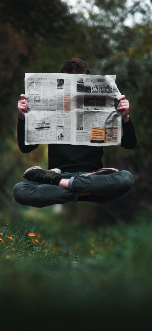 person holding a news paper during daytime iPhone 12 wallpaper 