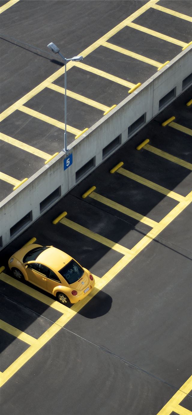 yellow coupe on parking lot at daytime iPhone 12 wallpaper 