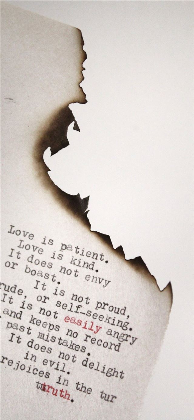 Love is patient Love is kind printed on burned pap... iPhone 12 wallpaper 
